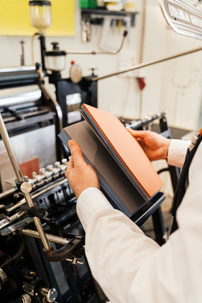 gallery-02 Person holding papers near a printing press in a workshop setting.